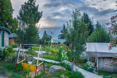 a garden with a swing and a playground at The Monk Campsite by Livingstone in Kalpa