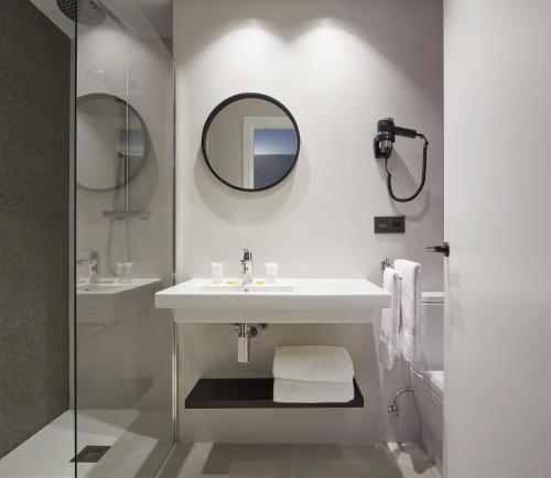 a white bathroom with a sink and a mirror at HOTEL ARRiZUL BEACH in Donostia-San Sebastián