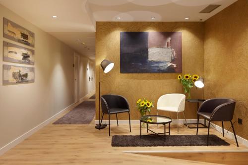 a hallway with chairs and a table and a painting at Hotel Arrizul Beach in San Sebastián