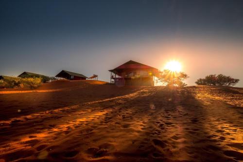 a dirt road in front of a building with the sunset at Bagatelle Kalahari Game Ranch in Hardap