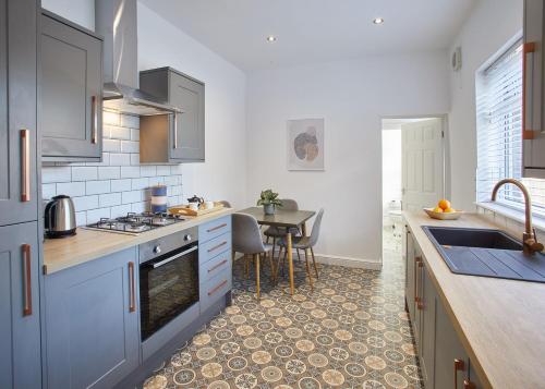 een keuken met blauwe kasten en een tafel bij Host & Stay - The Ruby Retreat in Saltburn-by-the-Sea