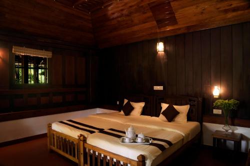 a bedroom with a large bed in a room with wooden walls at StayVista at La Riva Heritage Villa with Bicycle in Alleppey