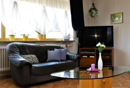 uma sala de estar com um sofá de couro e uma mesa de vidro em Ferienwohnung Röhrer em Obertrubach
