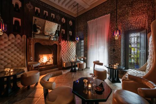a room with a fireplace and chairs and a table at Le Farnatchi in Marrakesh