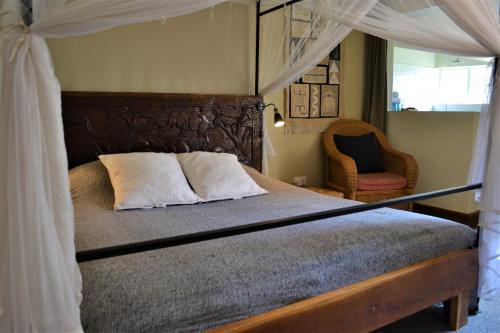 a bedroom with a canopy bed and a chair at Africa House Malawi in Lilongwe