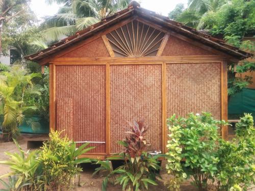 a small wooden house in a garden at Village Susegat Beach Resort in Morjim