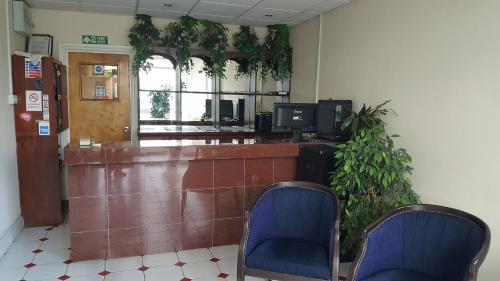 a waiting room with two blue chairs and a counter at Airport Guest House in Slough