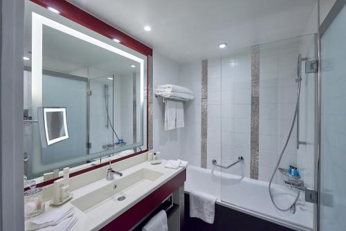 La salle de bains est pourvue d'un grand miroir, d'un lavabo et d'une douche. dans l'établissement Disney Hotel New York - The Art of Marvel, à Chessy