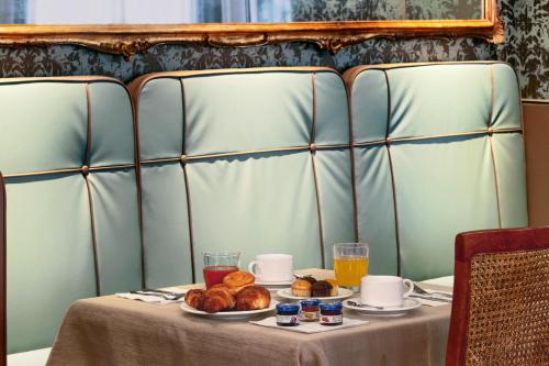 a table with a plate of pastries and orange juice at Hotel Bisanzio in Venice