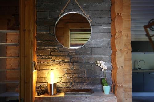 un mur en pierre avec un miroir et une bougie sur une table dans l'établissement COCOONING, à Gérardmer