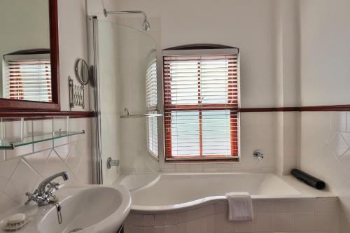 a white bathroom with a tub and a sink at Berg en Zee Guesthouse in Gordonʼs Bay