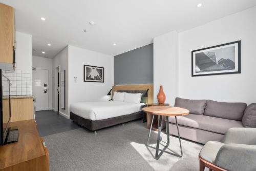 パースにあるAll Suites Perthのベッドとソファ付きのホテルルーム