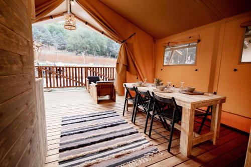 a room with a table and chairs on a deck at Glamping Can Bora Lodges in Las Serras