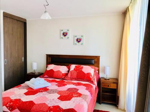 1 dormitorio con 1 cama con edredón rojo y blanco en Full Moneda 909, en Santiago