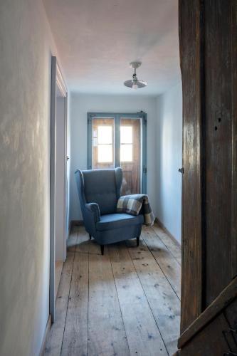 a living room with a blue chair and a window at Schlosserhaus Lam in Lam
