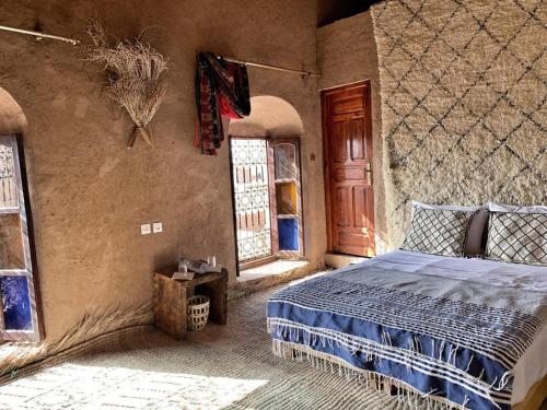 a bedroom with a bed in a room with windows at Kasbah Oulad Othmane in Aguebt