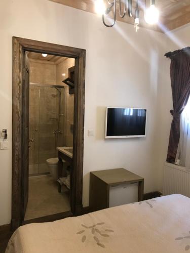 a bedroom with a shower and a television on the wall at Eskiciler Konağı in Egirdir