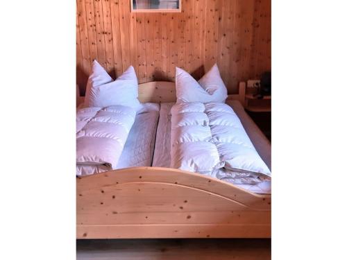 una cama de madera con almohadas blancas. en Gerda's Ferienhäuser en Eppenschlag