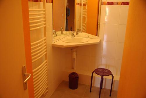 a bathroom with a sink and a mirror and a stool at Chambres d'hôtes La Fontaine Garel in Iffendic