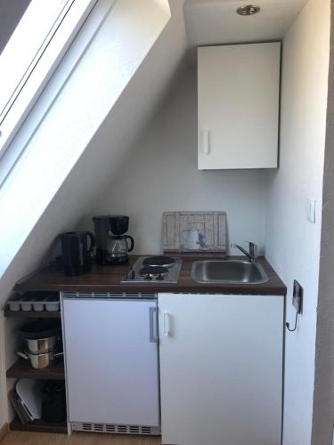una cocina con armarios blancos y un lavabo en un ático en Ferienwohnung 2 Basthorst, en Basthorst