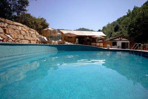uma grande piscina azul com uma casa ao fundo em Can Bora Lodges em Las Serras