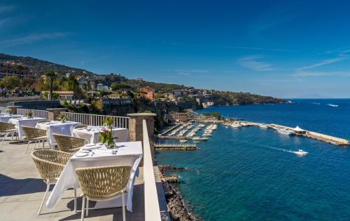 a row of tables and chairs on a balcony overlooking the water at Hotel Lorelei Londres in Sorrento