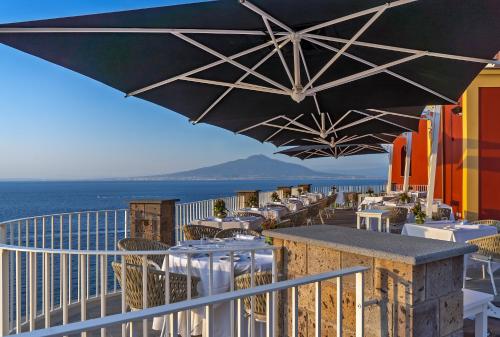 a patio with tables and chairs and an umbrella at Hotel Lorelei Londres in Sorrento