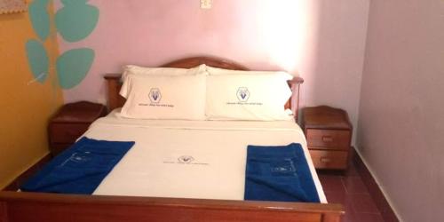 a bedroom with a bed with blue sheets and pillows at Miryams Village Inn Safari Lodge in Sultan Hamud