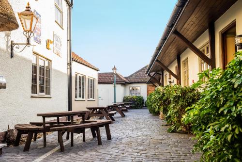 a row of wooden benches on a brick walkway next to buildings at The Half Moon Inn and Country lodge in Yeovil