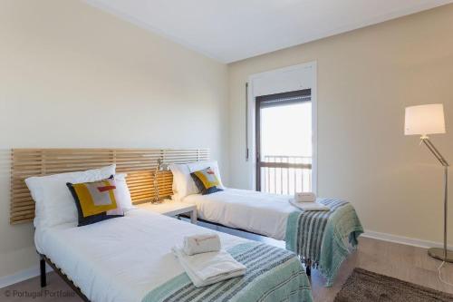 Cascais Panoramic Apartment في كاسكايس: سريرين في غرفة بيضاء مع نافذة