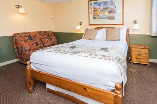 a bedroom with a large bed and a chair at The Half Moon Inn and Country lodge in Yeovil