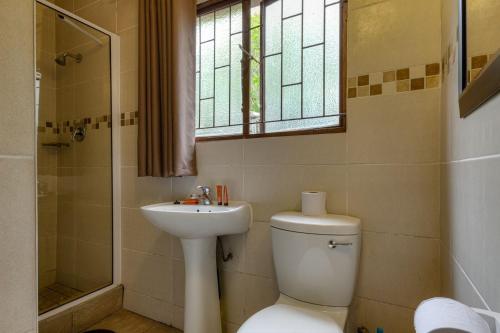 a bathroom with a toilet and a sink and a window at Shonalanga Lodge in St Lucia