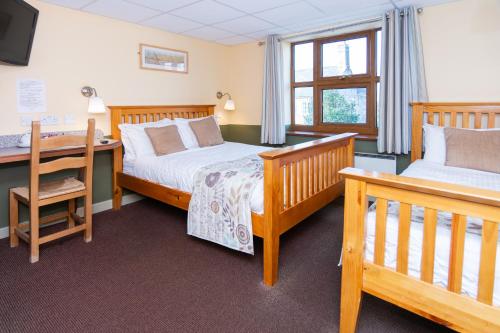 a bedroom with two beds and a desk at The Half Moon Inn and Country lodge in Yeovil