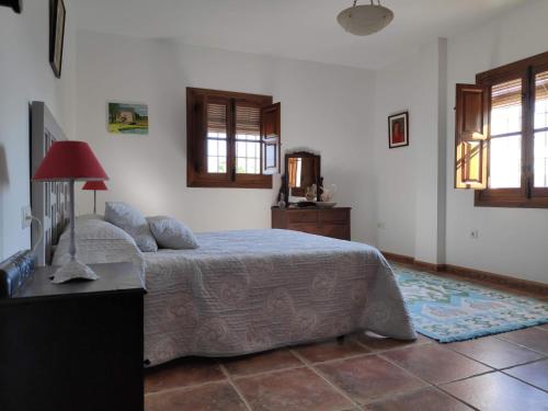 um quarto com uma cama, uma mesa e janelas em Cortijo El Arrejadero em Villanueva del Rosario