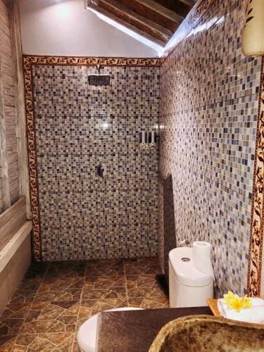 a bathroom with a shower and a toilet and a sink at The Lucky Cottage in Nusa Lembongan