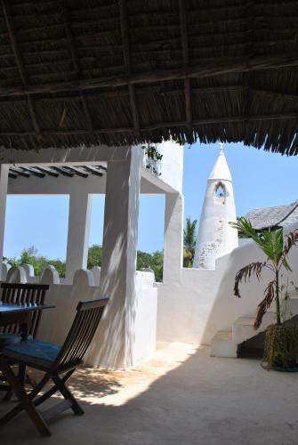 a chair under a roof with a tower in the background at Shella White House in Lamu