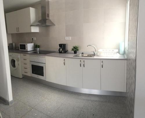 a white kitchen with a sink and a microwave at Apartamento de una habitación in Málaga