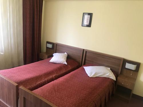 two beds in a hotel room with red sheets at Hotel Iasicon in Lacu Rosu