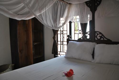 a red flower is sitting on a white bed at Shella White House in Lamu
