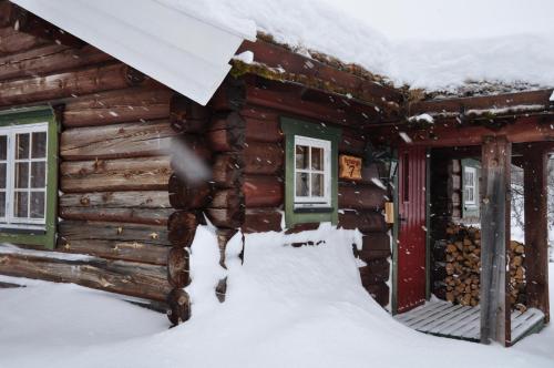 a log cabin in the snow with a horse standing outside at Rondane River Lodge - Rondane Gjestegård in Enden