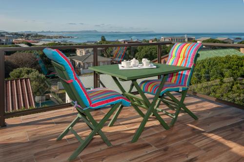 a green table and two chairs on a balcony at White Shark Guest House in Gansbaai