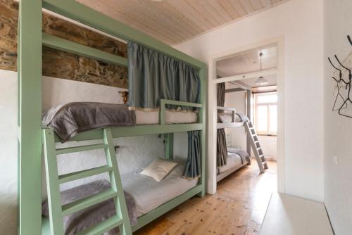 een groen stapelbed in een kamer met een ladder bij Bohemian Antique Guesthouse in Odeceixe