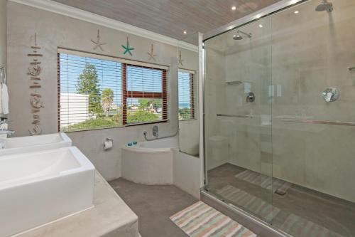 y baño con ducha, lavabo y bañera. en White Shark Guest House en Gansbaai
