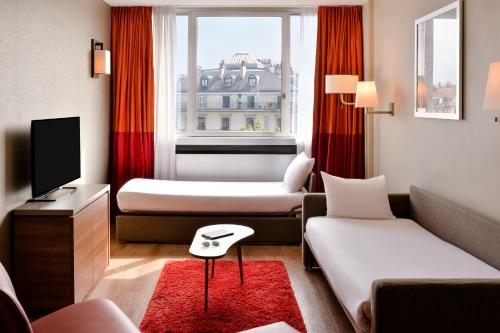 a hotel room with two beds and a television at Aparthotel Adagio Genève Mont-Blanc in Geneva