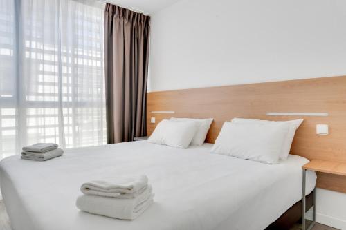 um quarto com uma cama com lençóis brancos e uma janela em Residhotel Galerie Tatry em Bordeaux