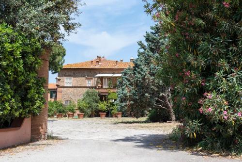 una grande casa è vista attraverso alcuni alberi di Fattoria Pian Di Rocca a Castiglione della Pescaia