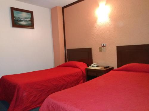a hotel room with two beds with red sheets at Hotel Maria Victoria Xalapa in Xalapa