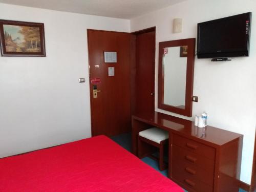 a bedroom with a red bed and a dresser with a mirror at Hotel Maria Victoria Xalapa in Xalapa