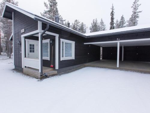 a black house with a porch in the snow at Holiday Home Pihkala 1 by Interhome in Äkäslompolo