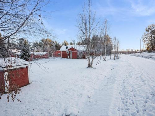 a snow covered yard with a red barn in the background at Holiday Home Nutukas-ylläksen lapikas by Interhome in Äkäslompolo